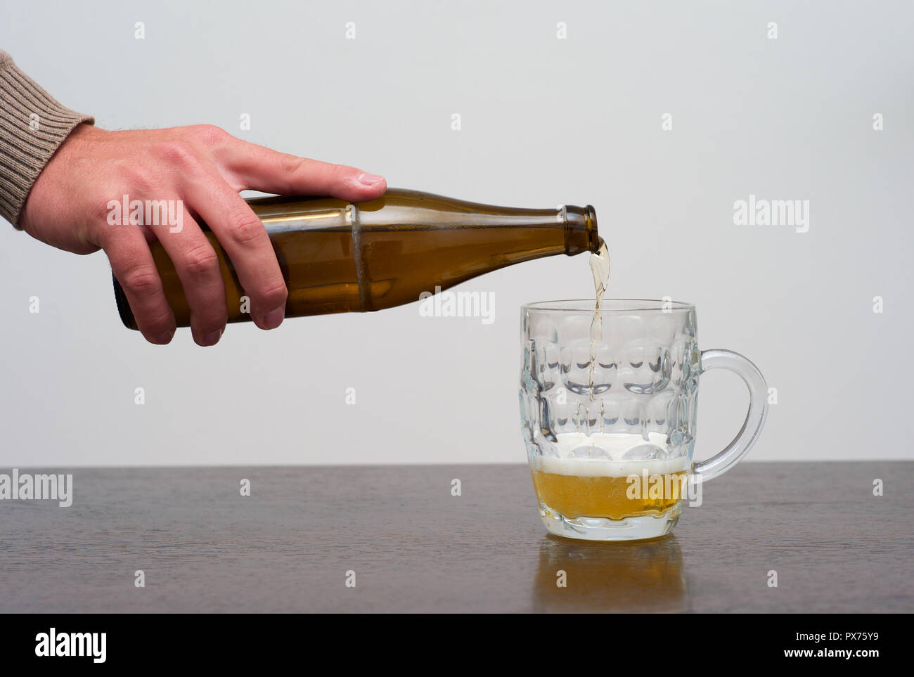 Filling a Pint of Blonde Beer from the Bottle, Hand Pouring Ale or Lager into a Tankard Stock Photo