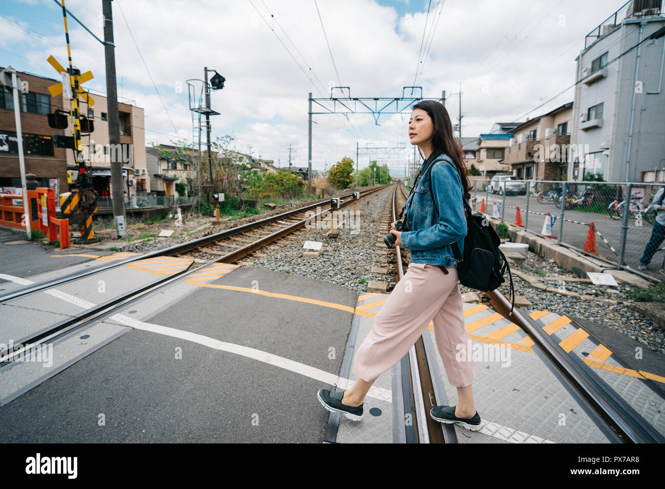 full length photo of an elegant female traveler crossing the railway. beautiful blue sky in sunny day. walking to sushi store for lunch in Kyoto. Stock Photo