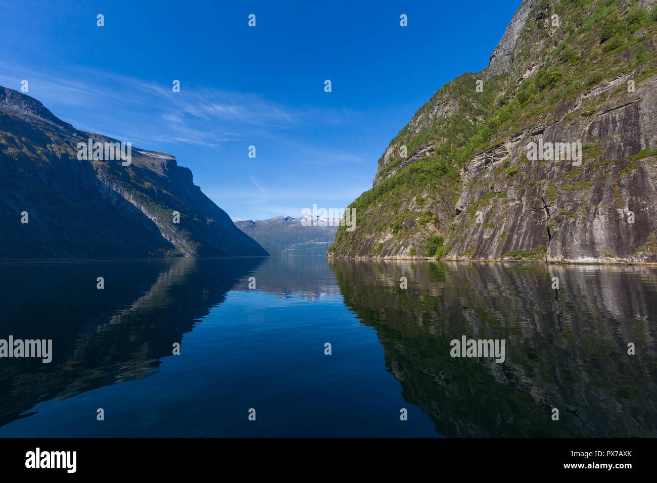 reflected mountains in Geiranger fjord, blue sky, sea Stock Photo