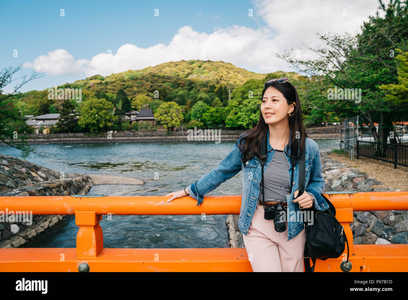 elegant asian traveler relying on the handrail on the bridge and enjoy the view. Japan vacation travel woman relaxing above the river. sightseeing in  Stock Photo