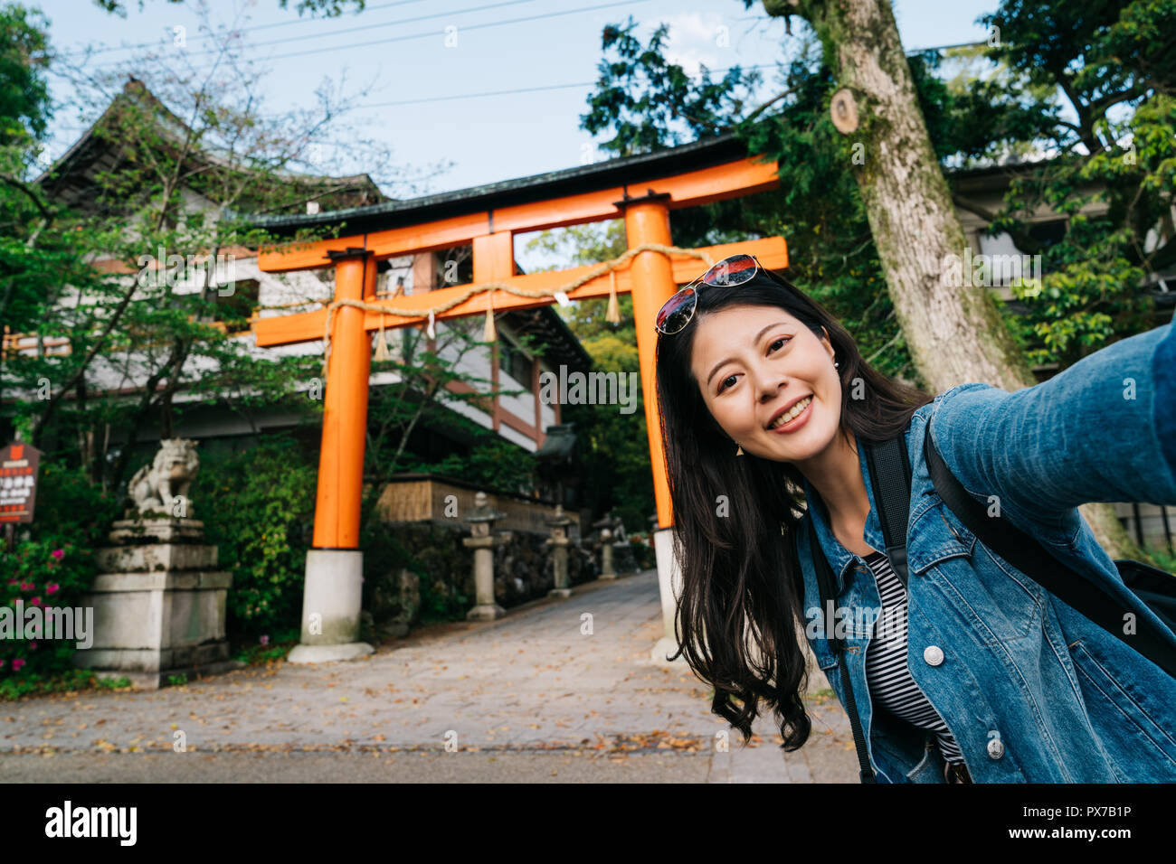 elegant traveler putting fashion sunglasses on her head and taking selfie with Torii. backpacker vacation selfie happy lady smiling taking photo with  Stock Photo