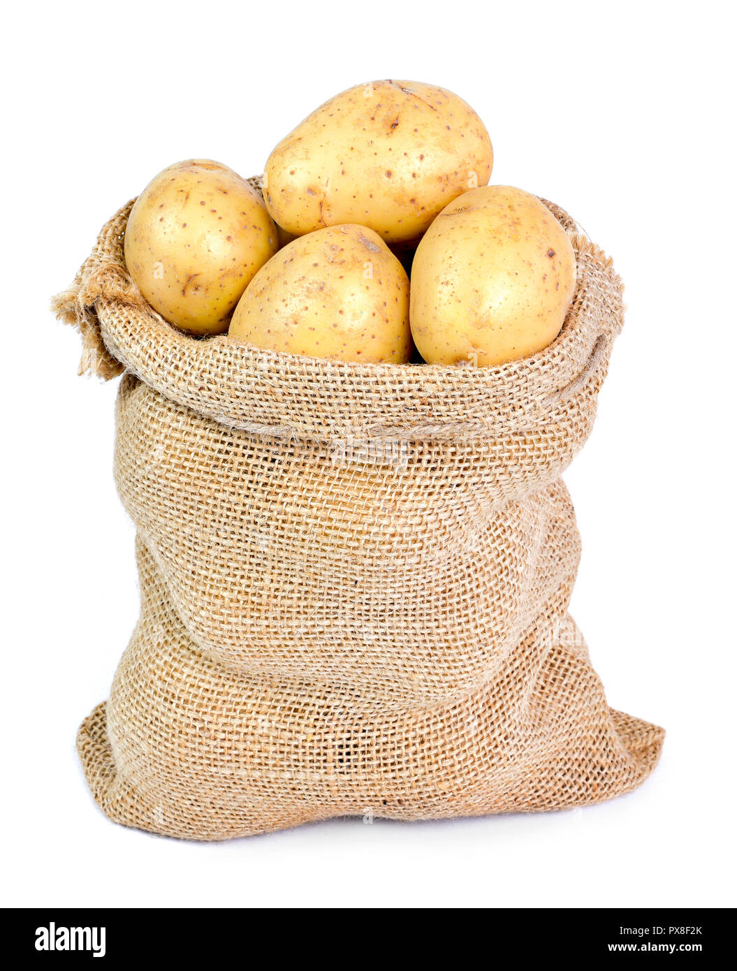 Fresh raw potatoes in a burlap sack. Earthy potato scene with Sackcloth isolated on white background, cooking ingredient. Stock Photo