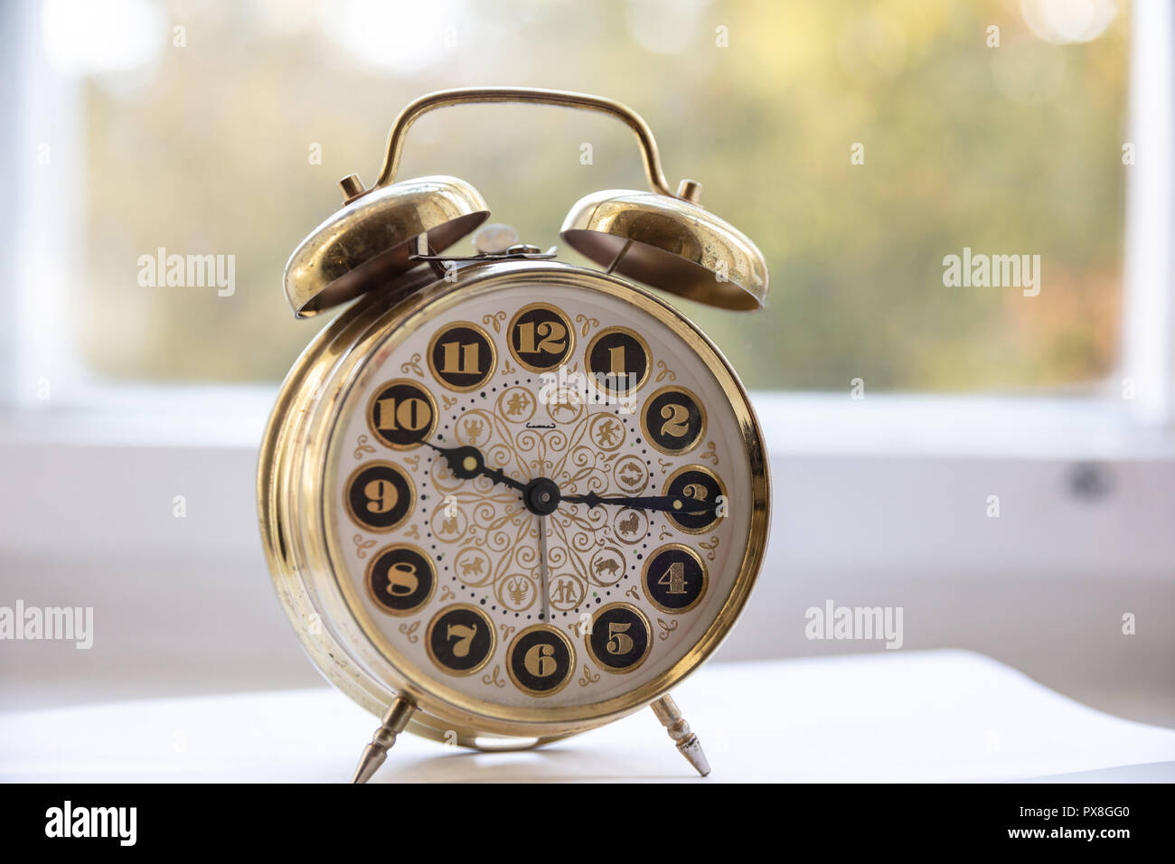 Time management. Golden alarm clock in the morning, blur glass window