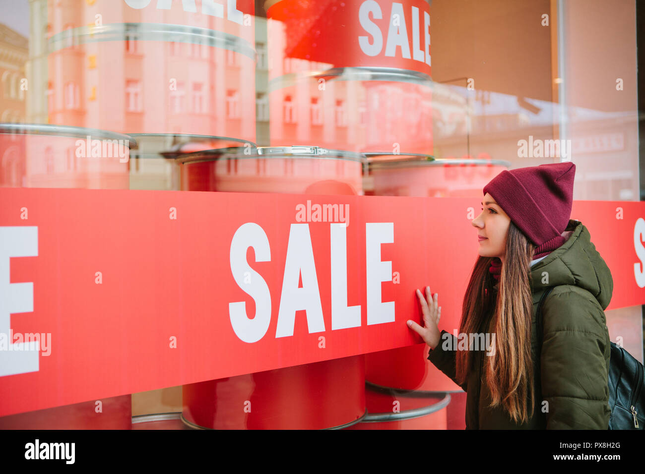 The girl at the storefront with a sale. Time of off-season and winter sales, Black Friday and Cyber Monday. Stock Photo