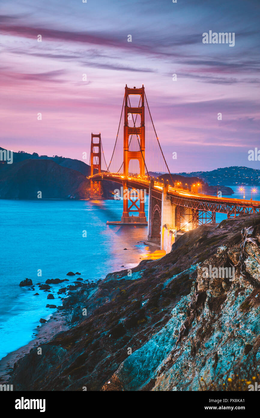 Classic panorama view of famous Golden Gate Bridge seen from scenic Baker Beach in beautiful post sunset twilight with blue sky and clouds at dusk in  Stock Photo