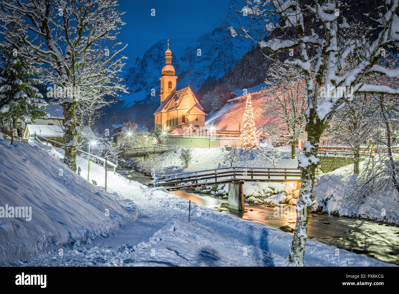 Beautiful twilight view of Sankt Sebastian pilgrimage church with decorated Christmas tree illuminated during blue hour at dusk in winter, Ramsau, Nat Stock Photo