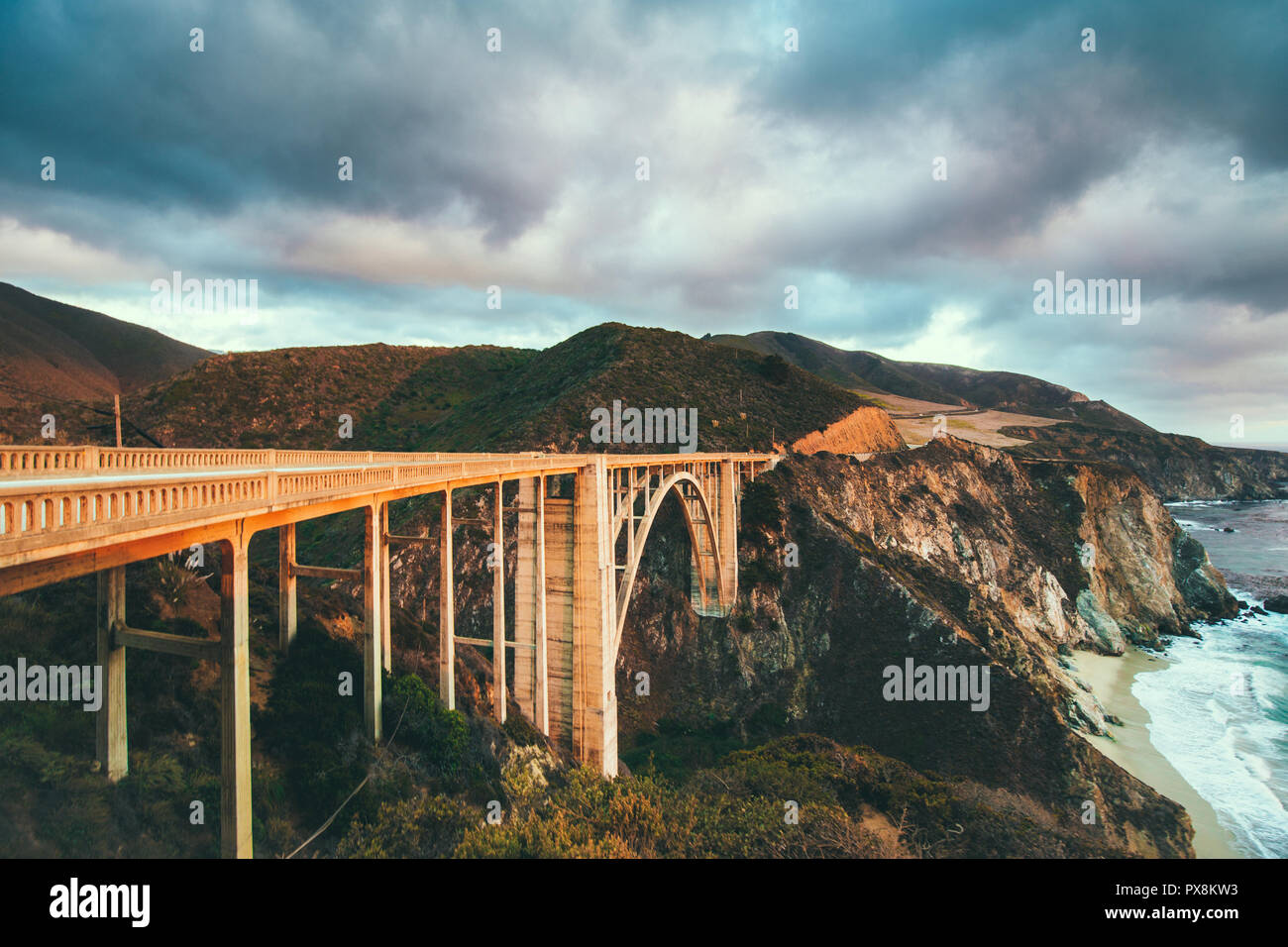 Scenic panoramic view of historic Bixby Creek Bridge along world famous Highway 1 in beautiful golden evening light at sunset with dramatic cloudscape Stock Photo