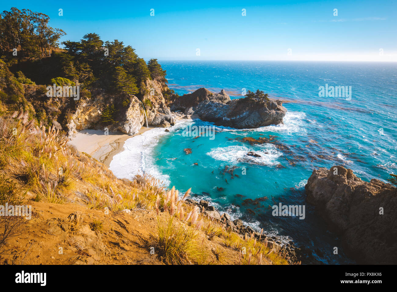 Classic postcard view of famous McWay Falls in scenic golden evening light at sunset on a beautiful sunny day with blue sky in summer, California, USA Stock Photo