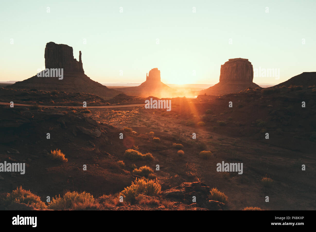 Classic view of scenic Monument Valley with the famous Mittens and Merrick Butte in beautiful golden morning light at sunrise in summer with retro vin Stock Photo