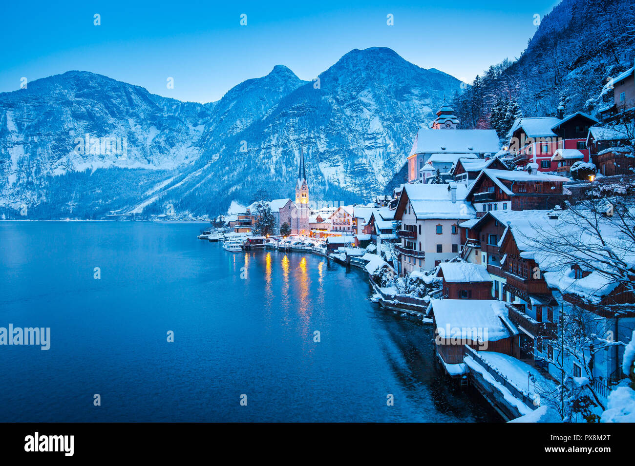 Classic postcard view of famous Hallstatt lakeside town in the Alps with beautiful Hallstattersee in mystical post sunset twilight during blue hour at Stock Photo