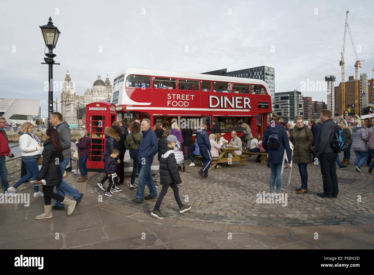 People walk past a double decker bus street food diner in the Albert Dock Liverpool UK Stock Photo