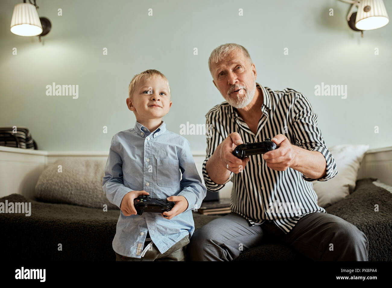 Grandfather and grandson playing video games on computer with joystick Stock Photo