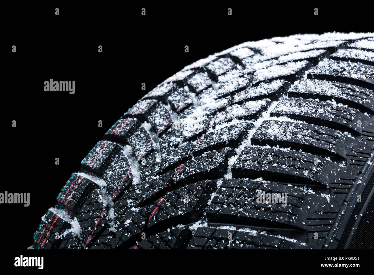 Winter car tires with snow wheel profile structure on black background - Close up. Stock Photo