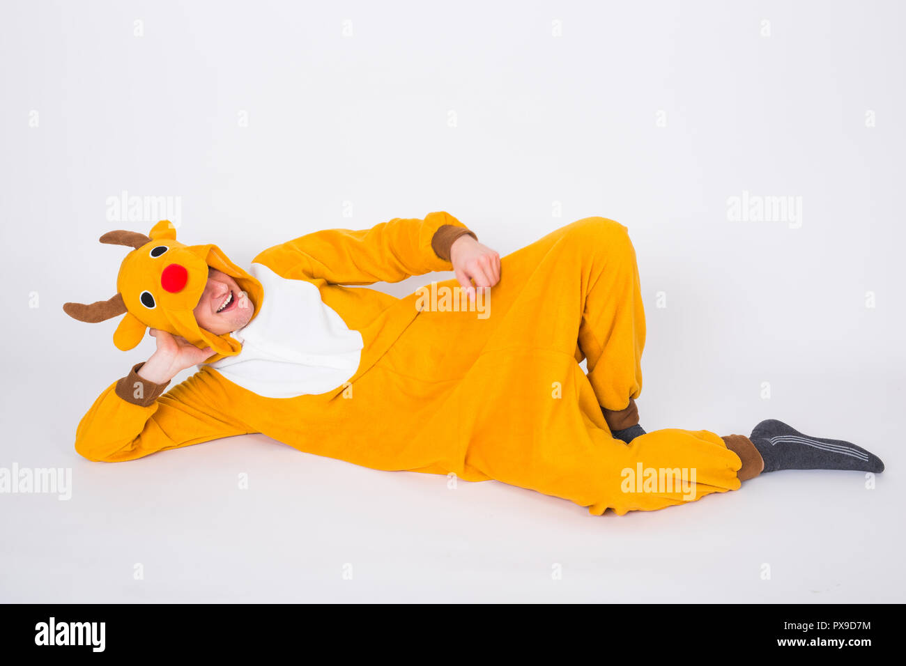Holiday, Christmas and people concept - Man in Santa Claus deer costume lying on the white floor Stock Photo