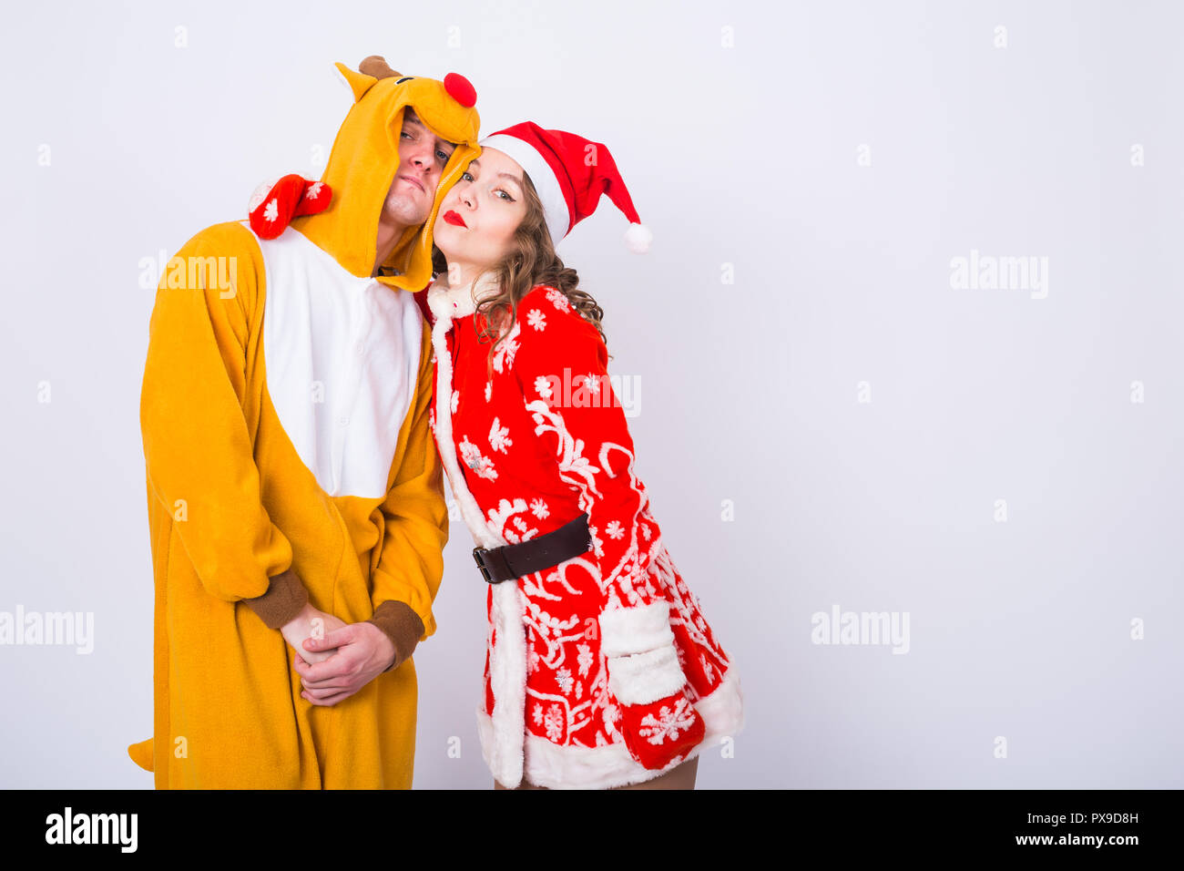 Holiday, Christmas and carnival concept - Funny couple in deer costume and Santa Claus costume have fun on white background with copy space Stock Photo