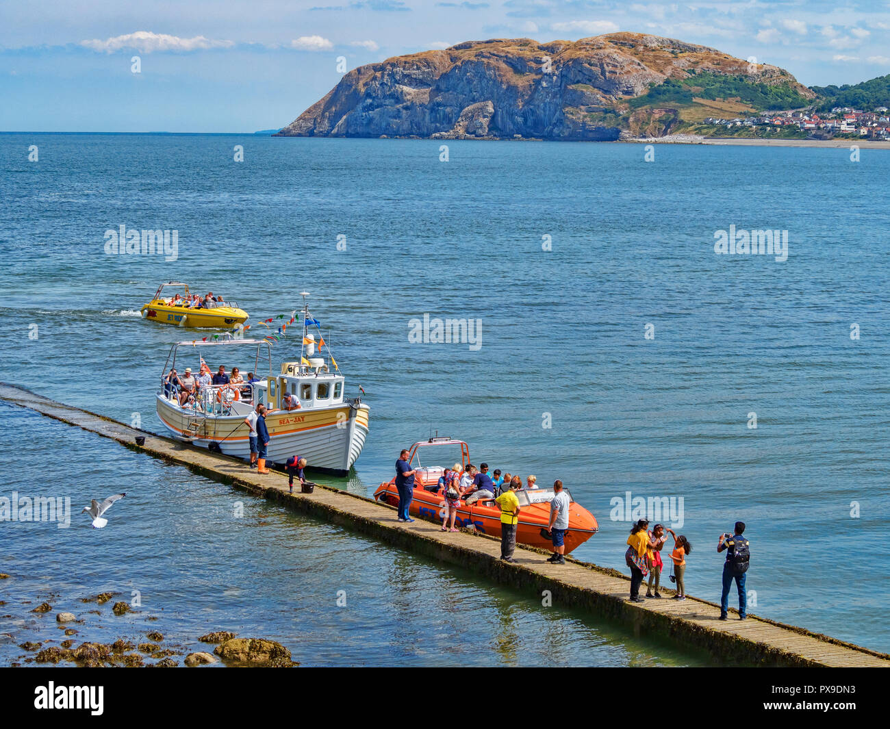25 July 2018: Llandudno; Conwy; UK - People on the boardwalk or jetty; getting on and off the Sea Jay and a Jet Boat; for rides around the bay, with.. Stock Photo