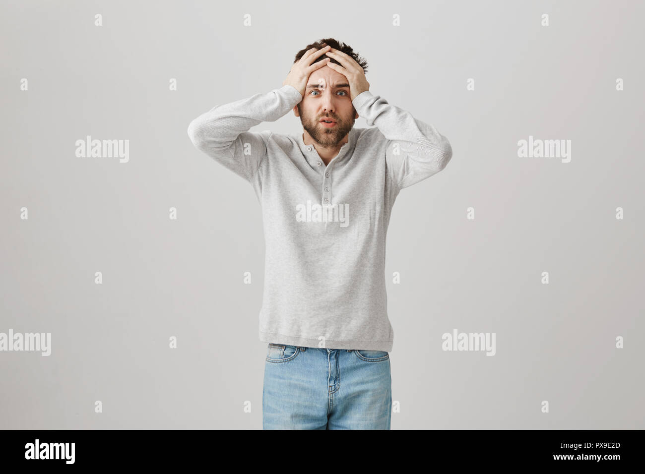 Unbelievable disaster. Worried devastated man, expressing shock and being in huge trouble, standing with hands on head and anxious expression, losing his job and wife. Life gone in wrong way Stock Photo