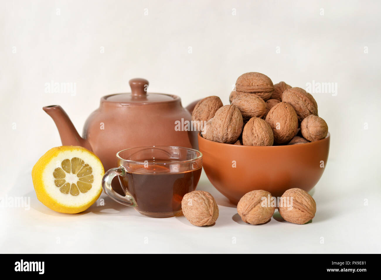 A Cup of tea, a kettle, a lemon and a bowl of nuts. Stock Photo