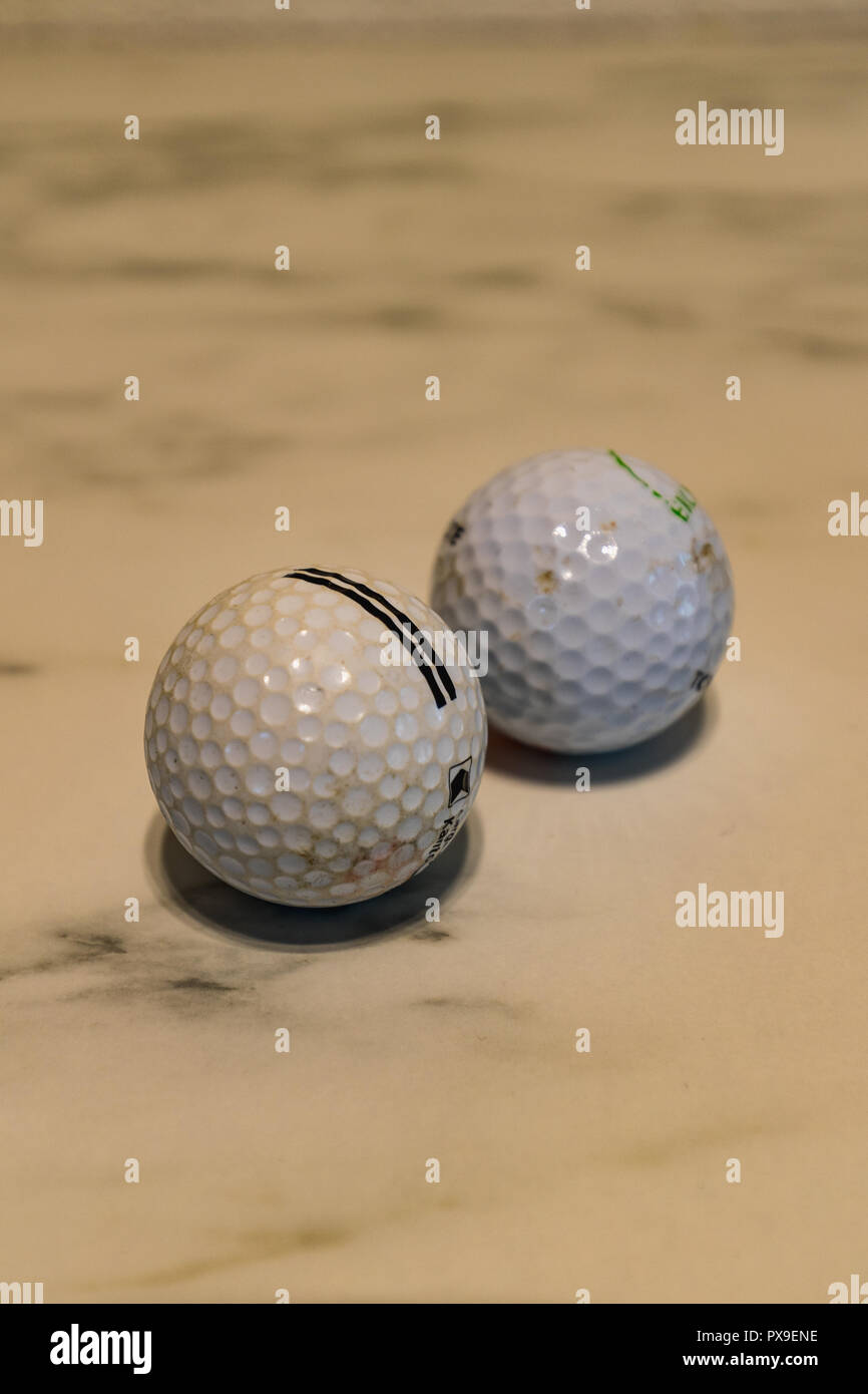 Set of two used dirty golf balls on a marble plate closeup Stock Photo