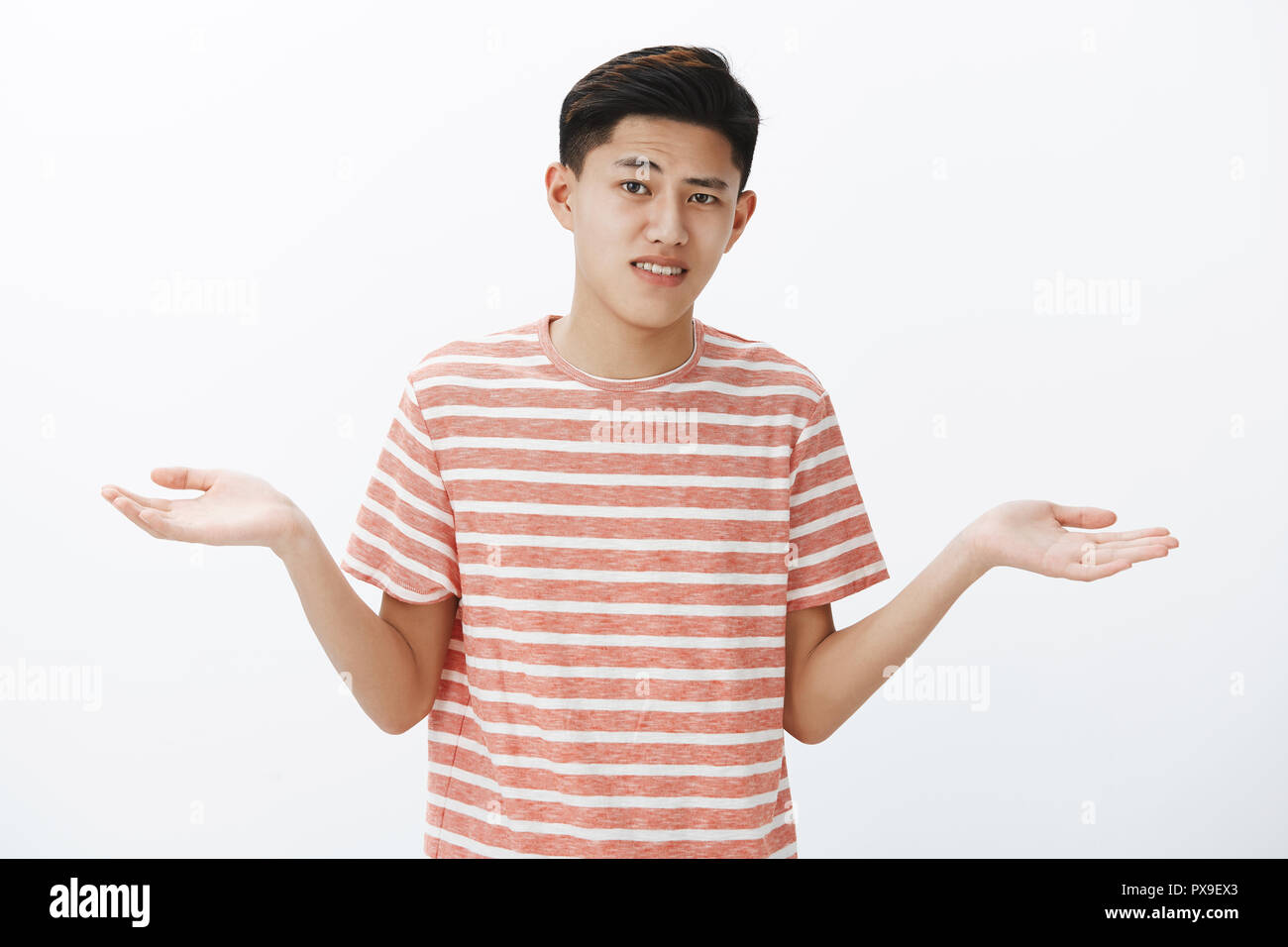 Hesitant Attractive Young Asian Guy With Dark Hair Shrugging