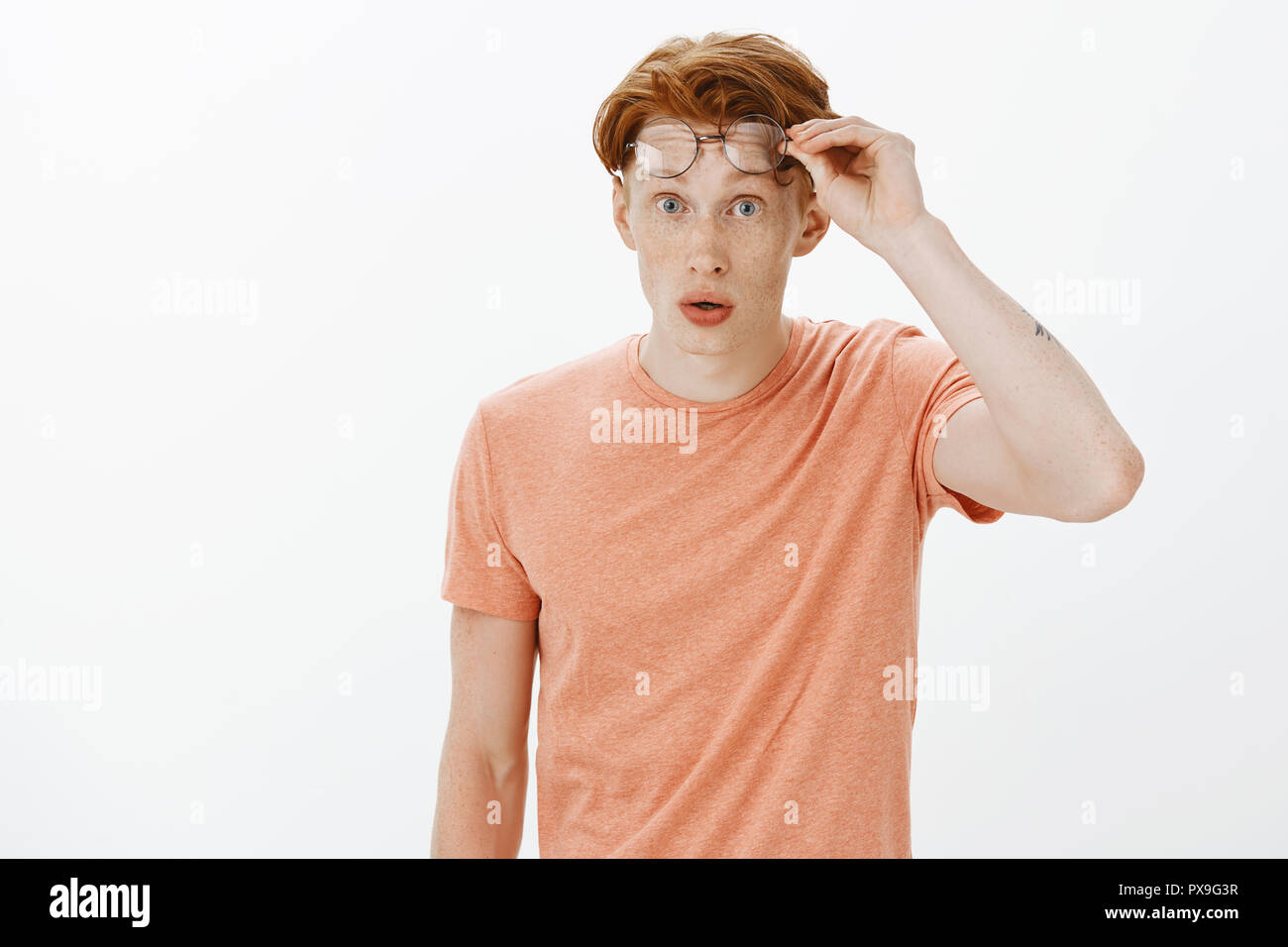 portrait-of-charming-nerdy-redhead-guy-with-freckles-in-orange-t-shirt-taking-off-glasses-and-gazing-with-amazement-and-surprise-at-camera-being-impressed-seeing-unbelievably-charming-classmate-PX9G3R.jpg