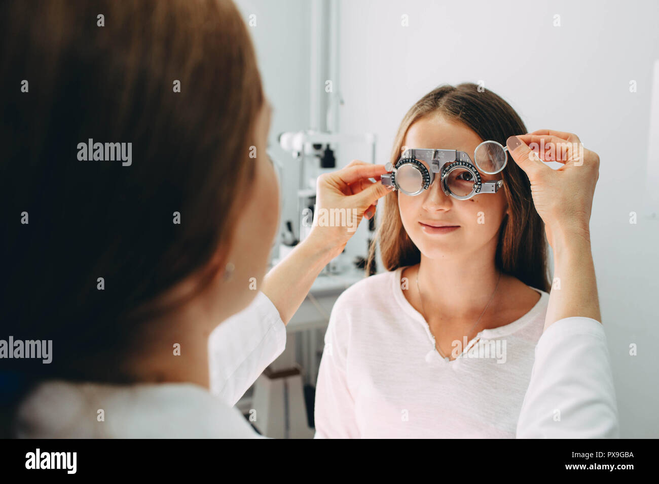 Eye doctor examining girls vision using a trial frame Stock Photo