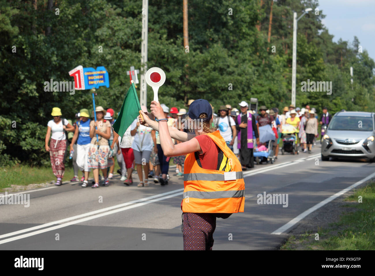 A young woman directs road traffic during pilgrimage to the Monastery of Jasna Gora in Czestochowa, Poland for the annual feast of Assumption of Mary. Stock Photo