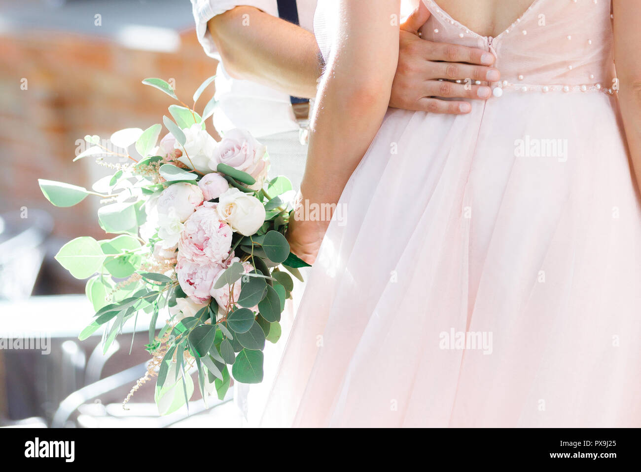 Hands of the bride and groom with wedding bouquet Stock Photo - Alamy