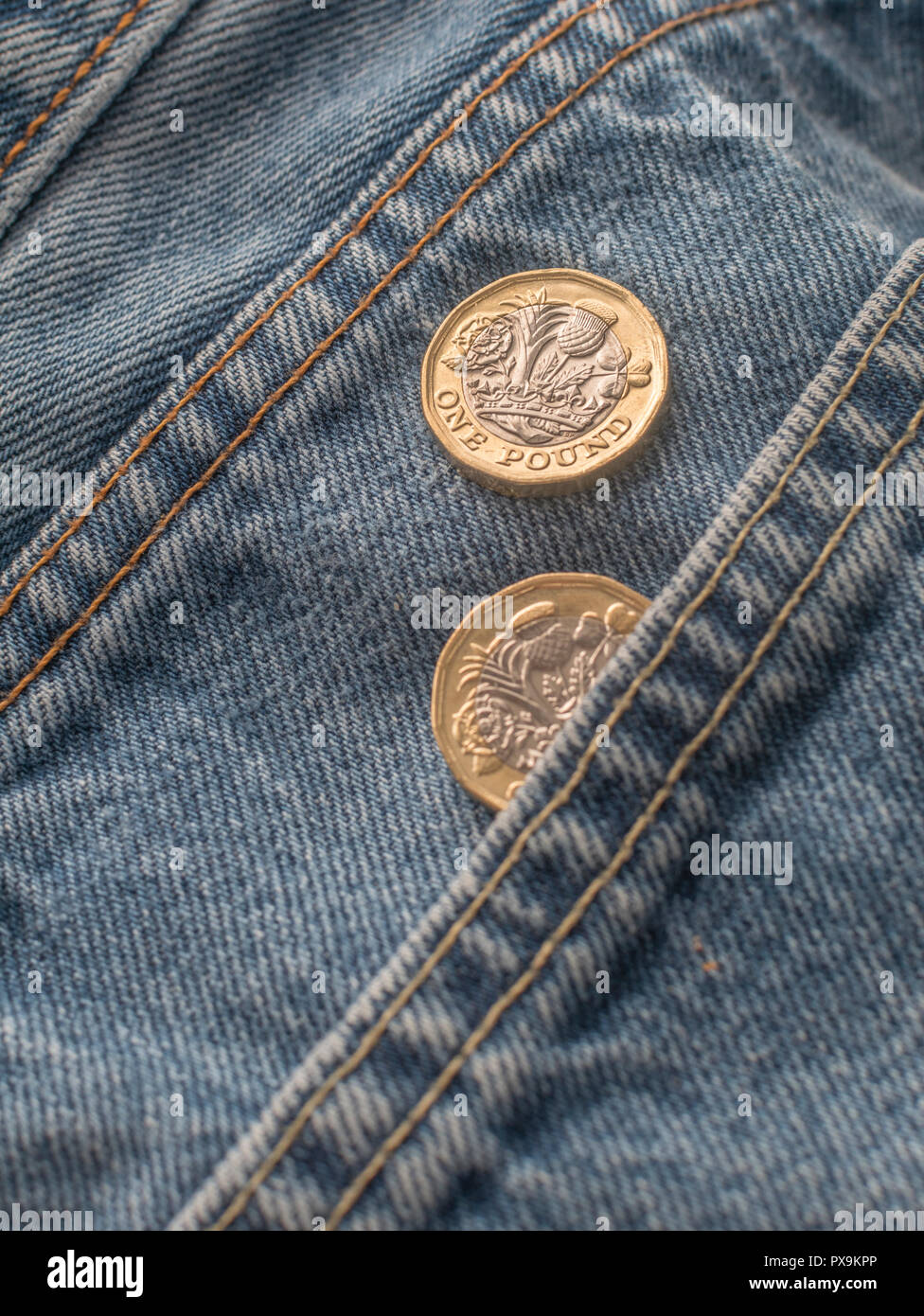 New Pound coin and trouser pocket. Metaphor for 'The Pound in Your Pocket' or pocket change, UK wages concept, Pound Sterling, last pound in pocket. Stock Photo