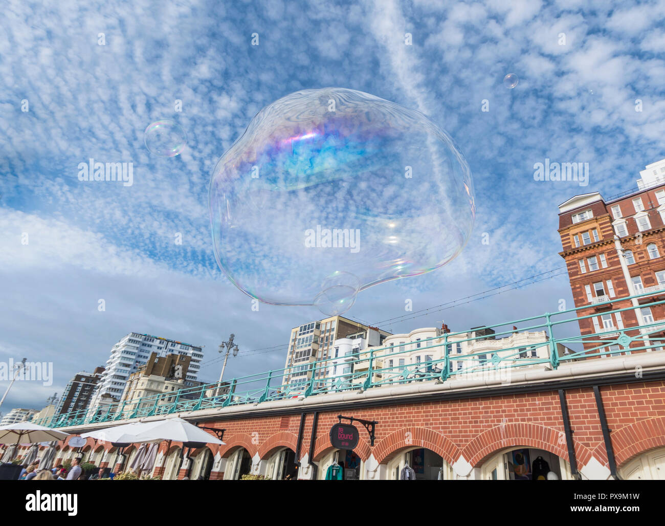 Large bubble floating in the sky in a city with blue sky & fluffy clouds in Brighton, UK. Freedom concept. Floating freely. Stock Photo