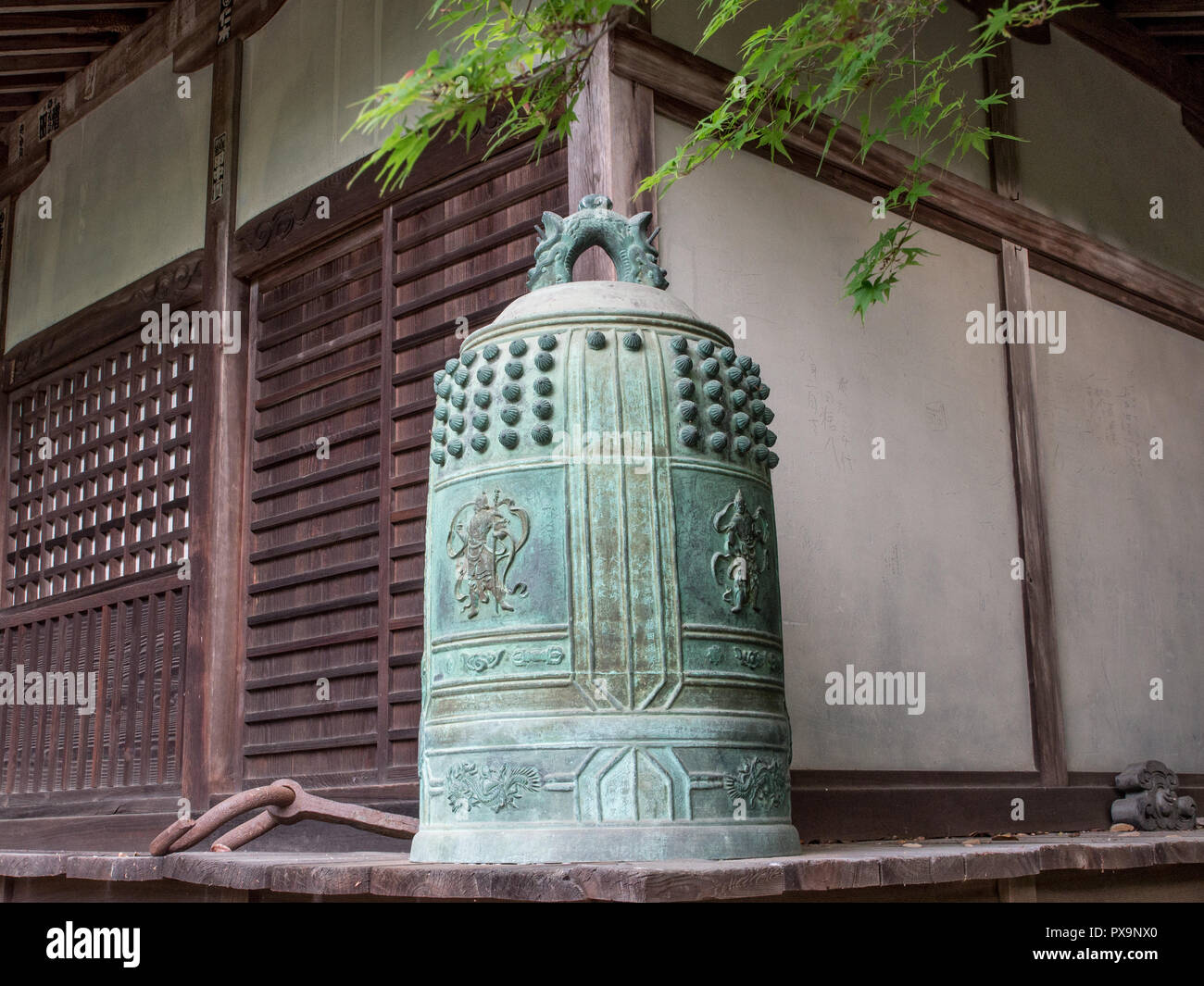Bronze temple bell,  on porch, dismounted, not hung,  spring momiji leaves,  Iyadaniji temple 71, Shikoku 88 temple pilgrimage, Kagawa, Japan Stock Photo