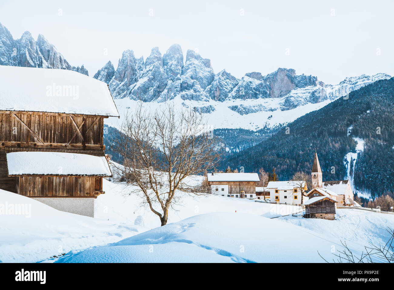 Classic panoramic view of famous Dolomites mountain peaks with the historic village of Val di Funes on a scenic day in winter, South Tyrol, Italy Stock Photo