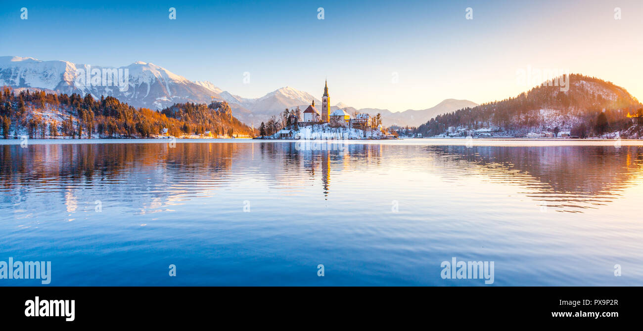 Beautiful view of famous Bled Island (Blejski otok) at scenic Lake Bled with Bled Castle (Blejski grad) and Julian Alps in the background in golden mo Stock Photo