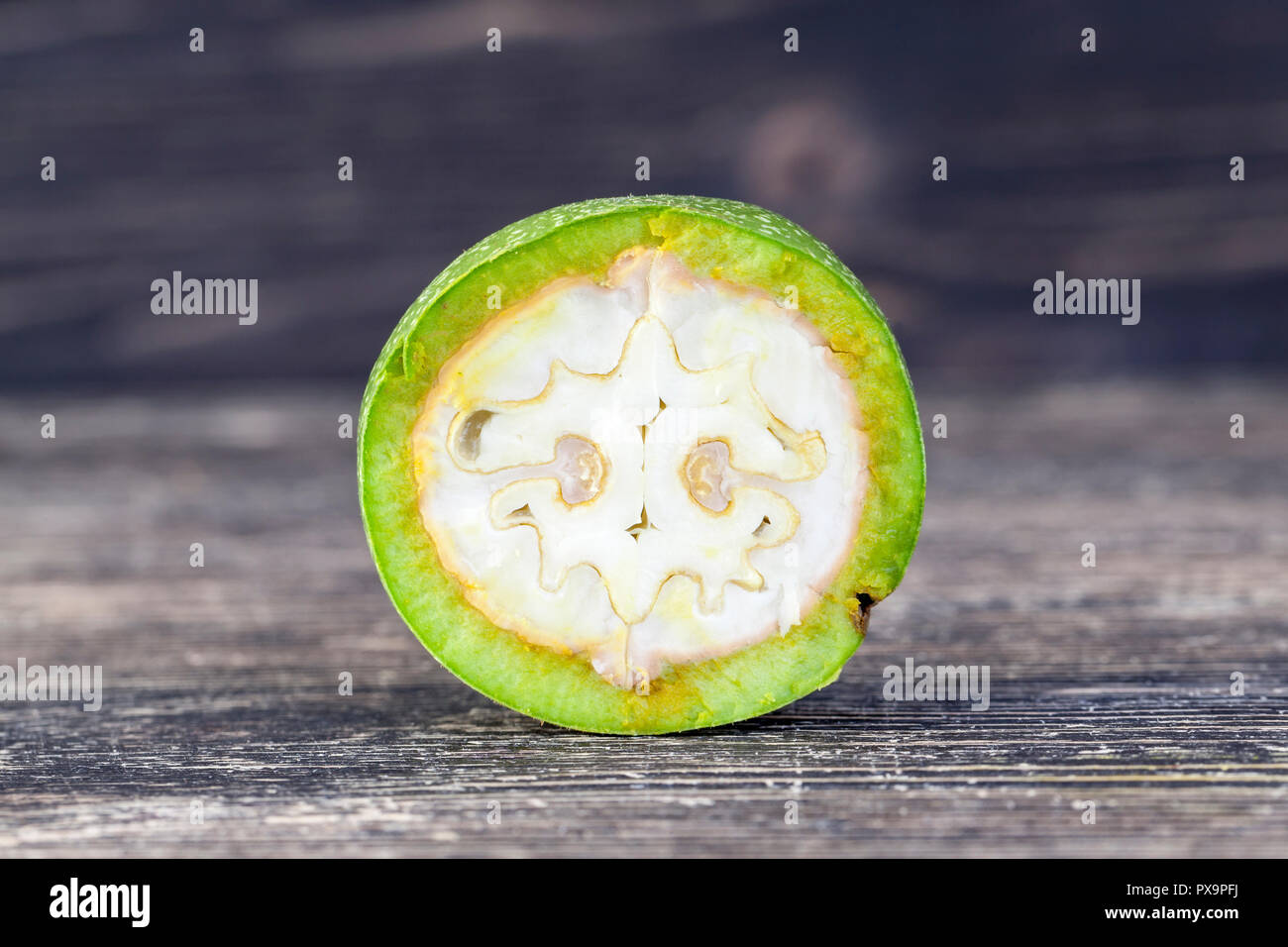 cut and broken piece of green walnut that is not ripe, on a black table Stock Photo