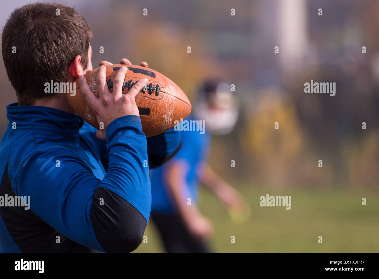 Team coach throwing the ball into the group of young american football players in action during