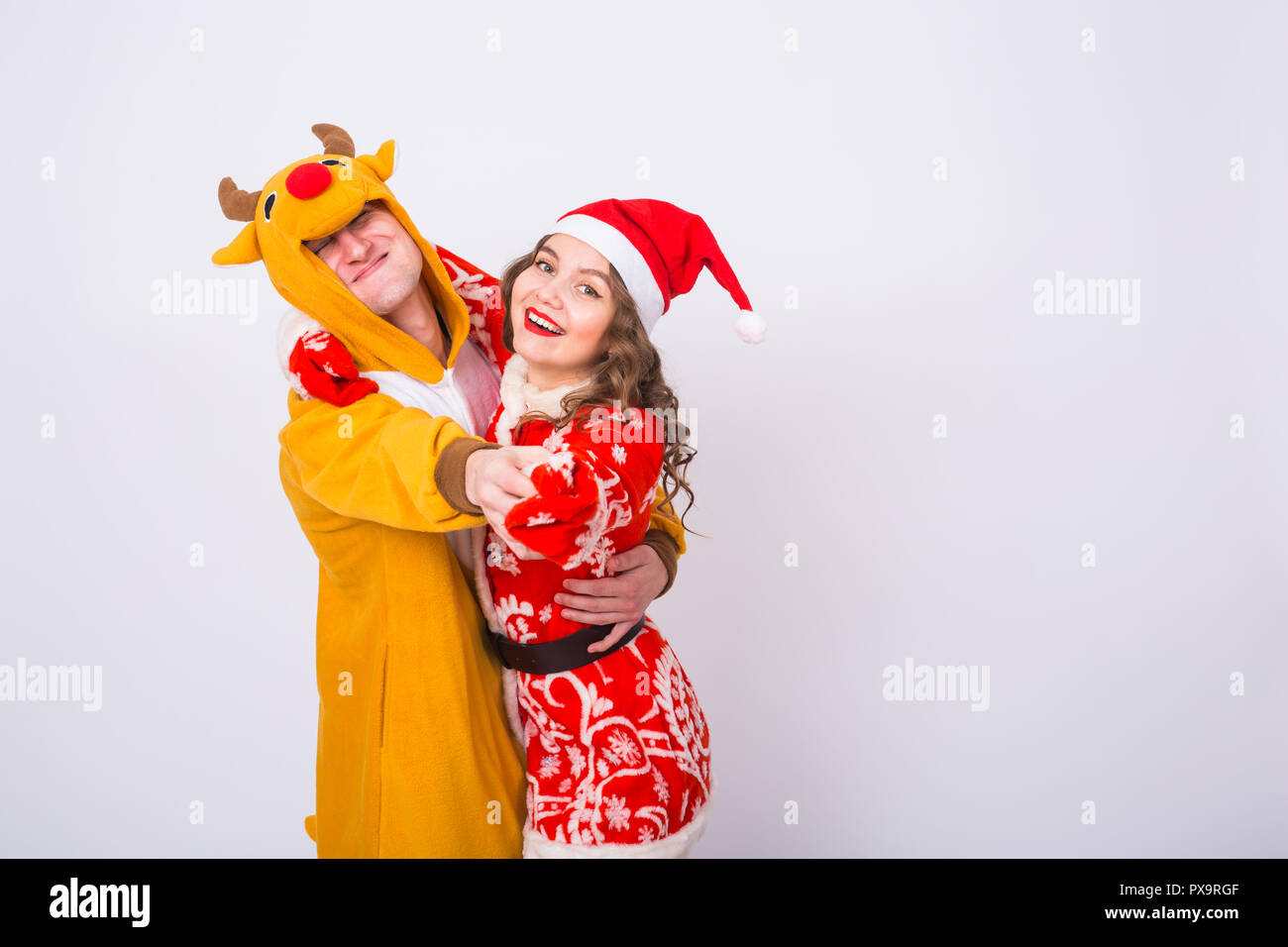 Holiday, Christmas and carnival concept - Funny couple in deer costume and Santa Claus costume have fun on white background with copy space Stock Photo