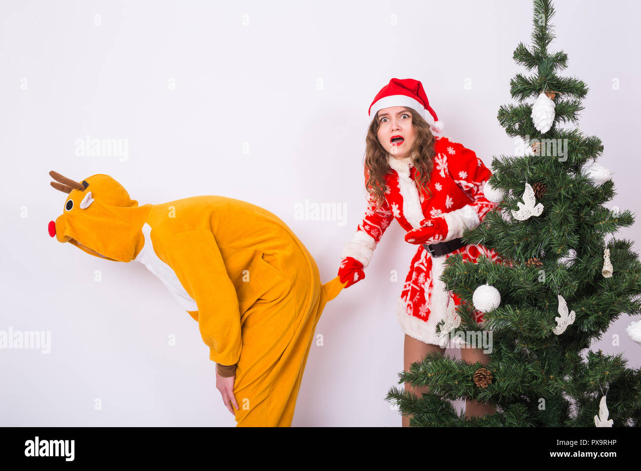 Fun, christmas and holidays concept - funny woman in santa suit holding the  tail of man in costume of deer on white background Stock Photo - Alamy