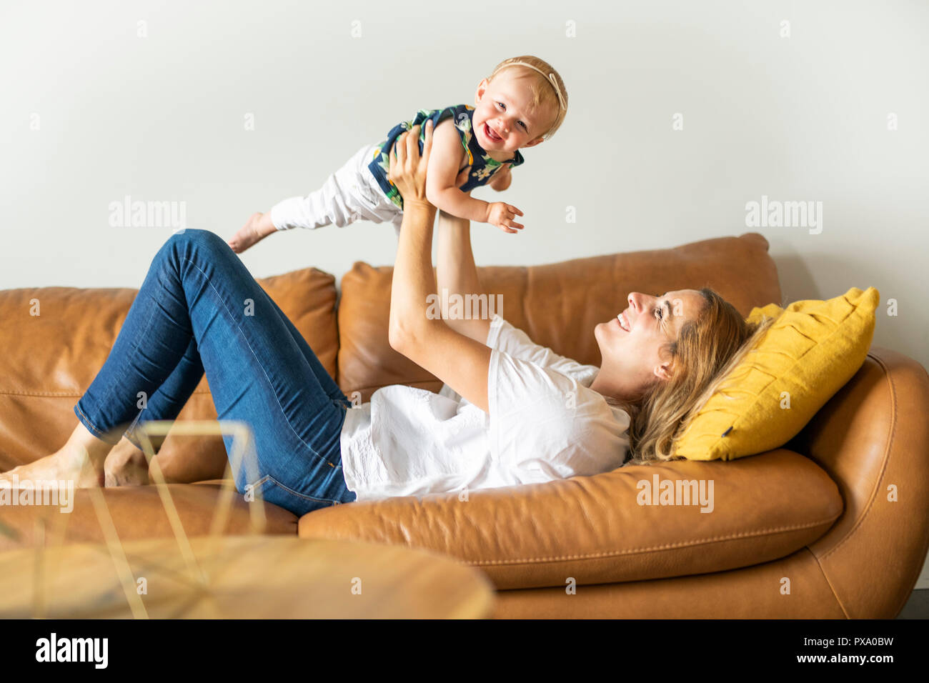 A happy family. Mother and baby daughter plays, on the sofa Stock Photo