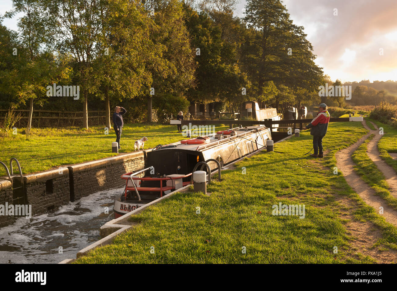 Conversation across canal barge at Catteshall Lock on the River Wey, Godalming, at sunset on a lovely summers evening, with calm tranquil conversation Stock Photo