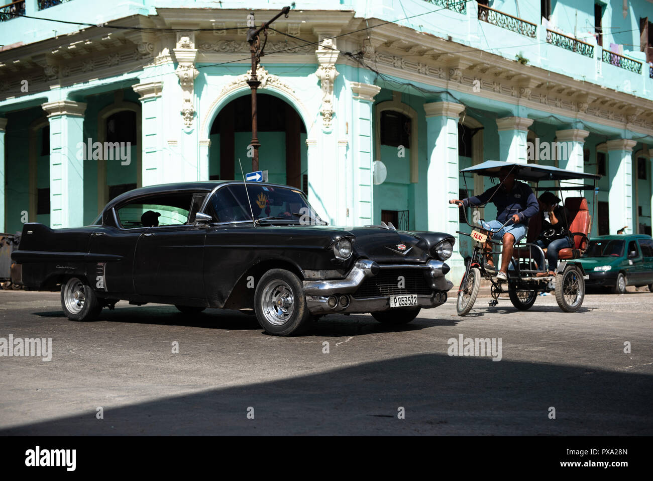 Road in old Havana with old black car and rickshaw. Stock Photo