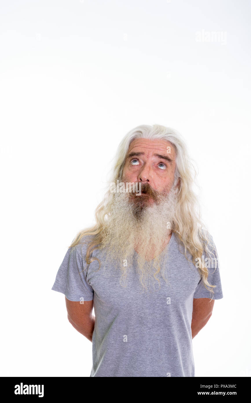 Studio shot of senior bearded man thinking while looking up with Stock Photo