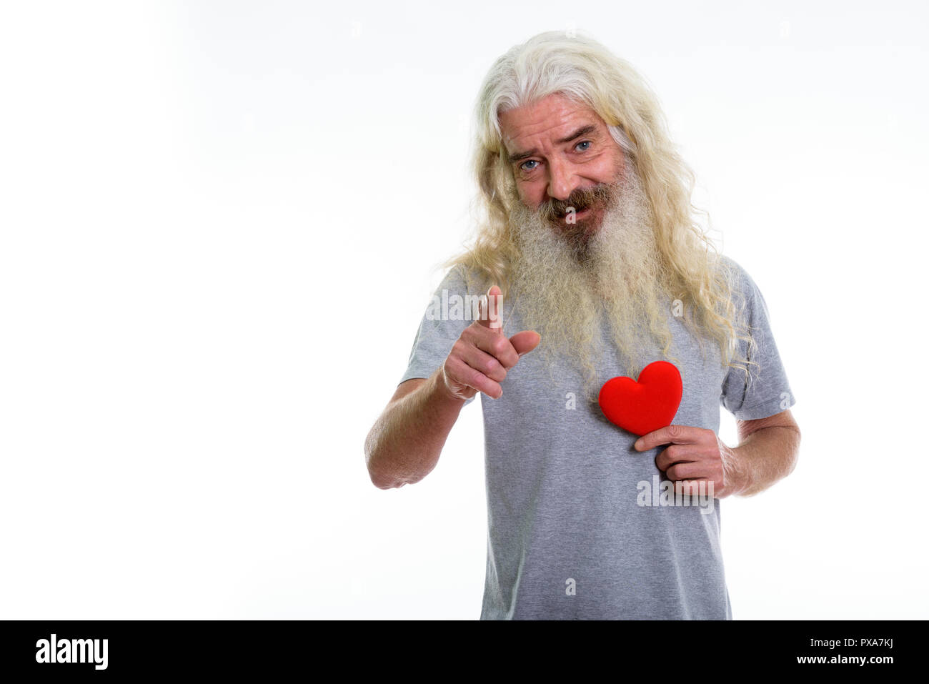 Studio shot of happy senior bearded man smiling and pointing at  Stock Photo