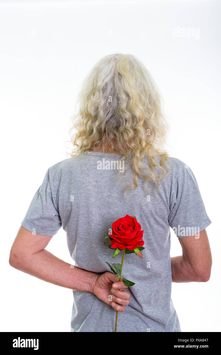Back view of senior bearded man hiding red rose behind back read Stock Photo