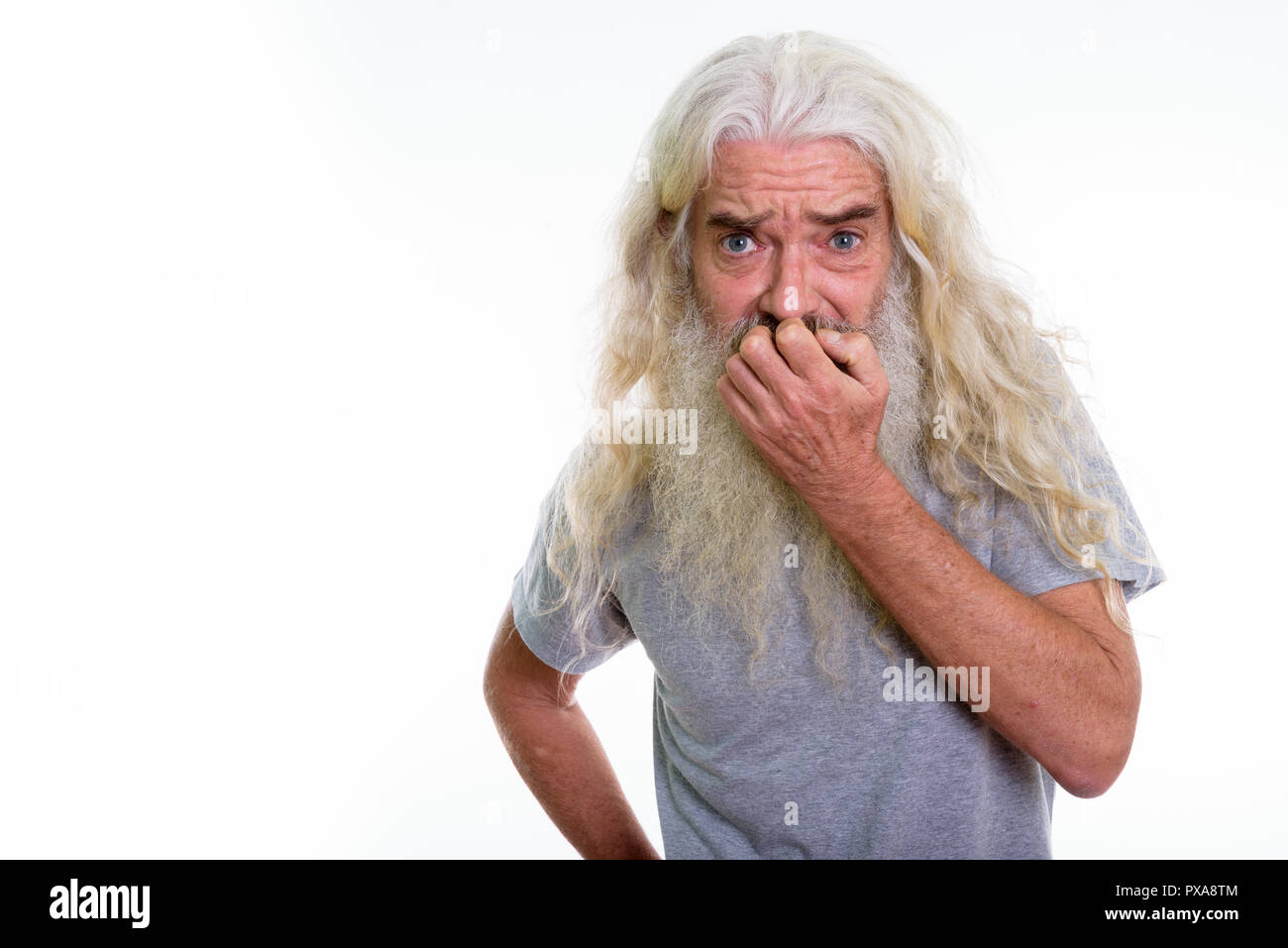 Studio shot of senior bearded man looking scared while covering  Stock Photo