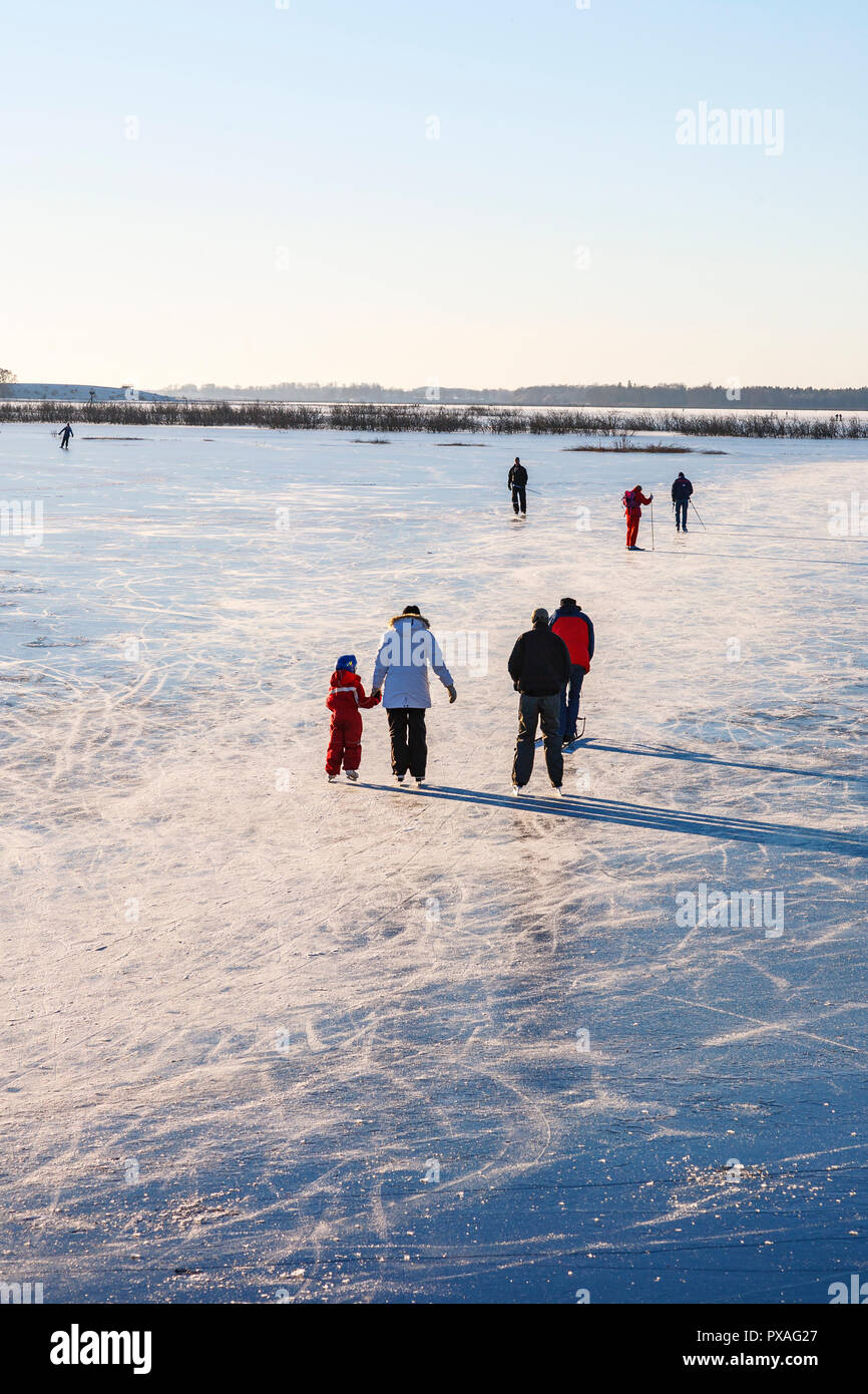 People that are ice skating at a frozen lake in the winter Stock Photo