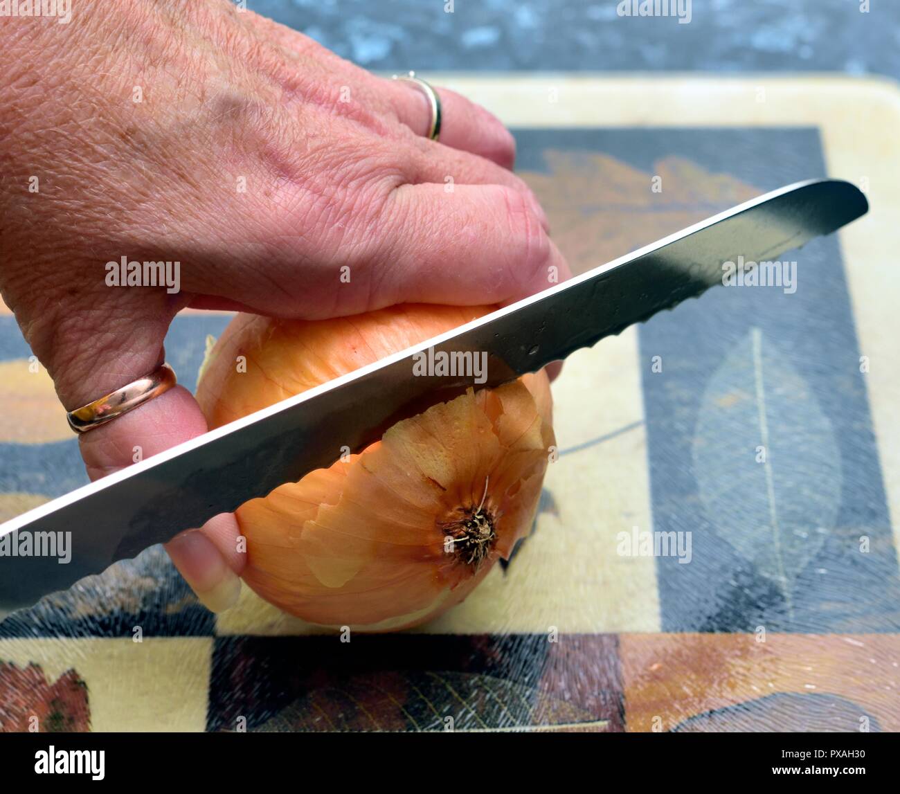 Cutting up a cooking onion on a chopping board Stock Photo