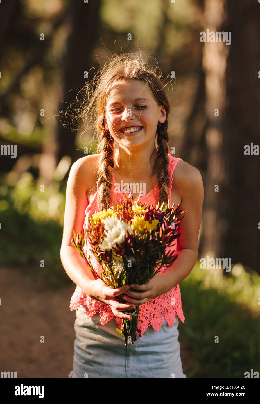 Happy girl with a bouquet of flowers in hand. Girl standing outdoors with a bunch of flowers in