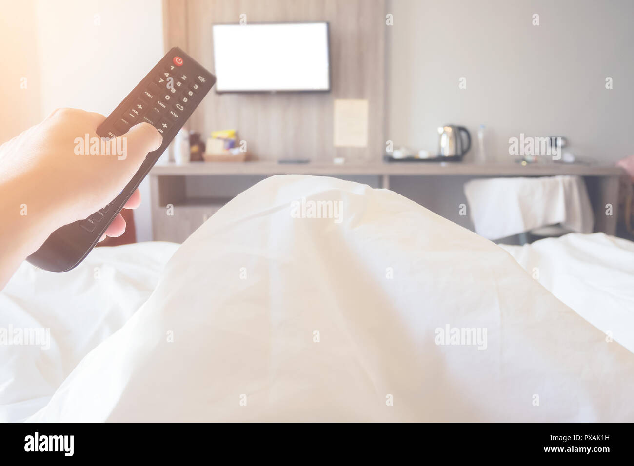 hand holding remote control television ob bed in bedroom close up Stock Photo