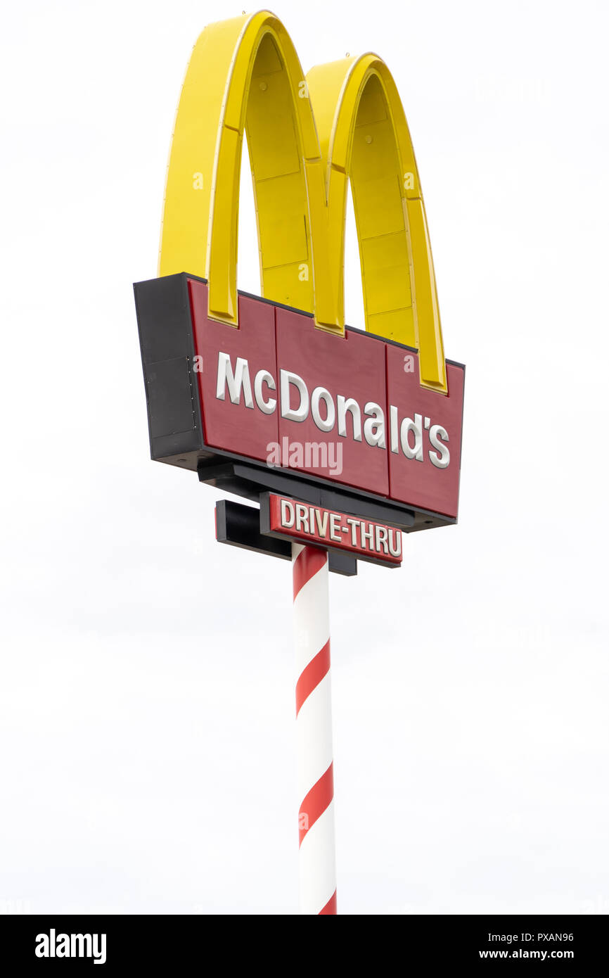 AUGUST 12 2018 - NORTH POLE, ALASKA: Artistic angle of a McDonalds sign and a tree Signpost is decorated like a candy cane to adhere to the Christmas  Stock Photo
