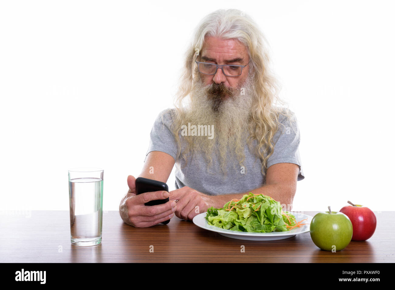 Studio shot of senior bearded man using mobile phone with health Stock Photo